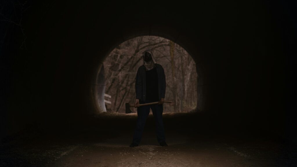 A picture of a dark man in the woods with an axe to represent slasher movies