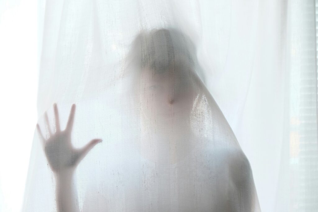 a creepy woman behind a sheer curtain  to represent how to write a short horror story